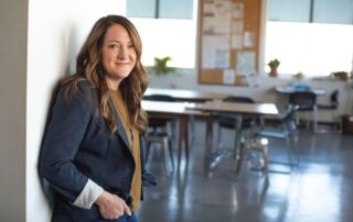 a woman leaning against a wall in a classroom