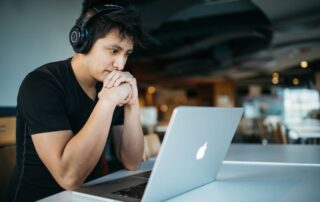 A student wearing black headphones looking at a laptop