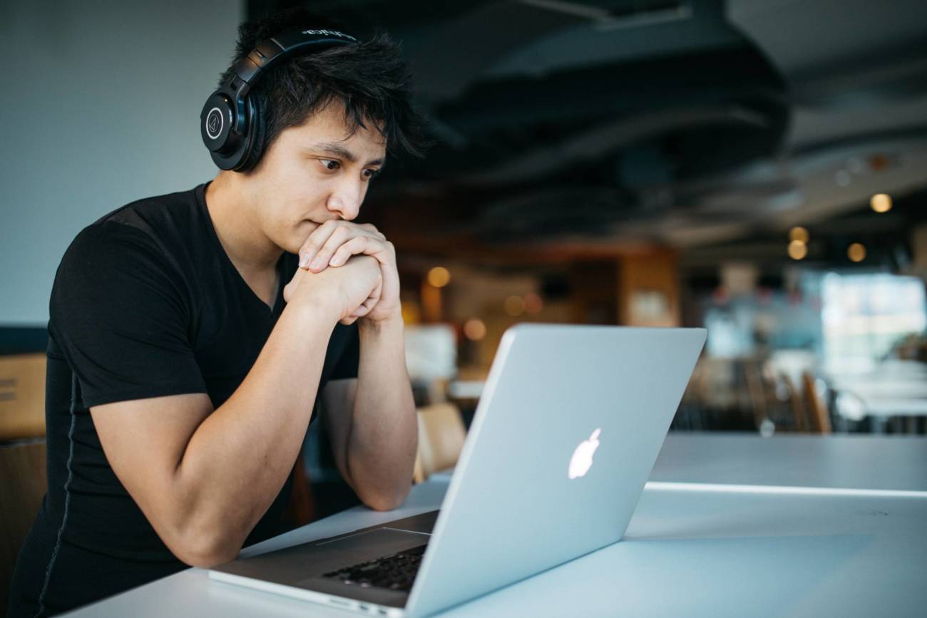 A student wearing black headphones looking at a laptop