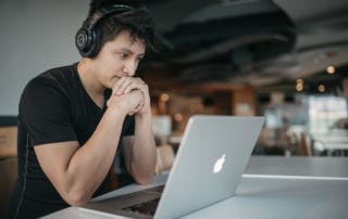 Depression at work - A young man wearing headphones looking at a laptop