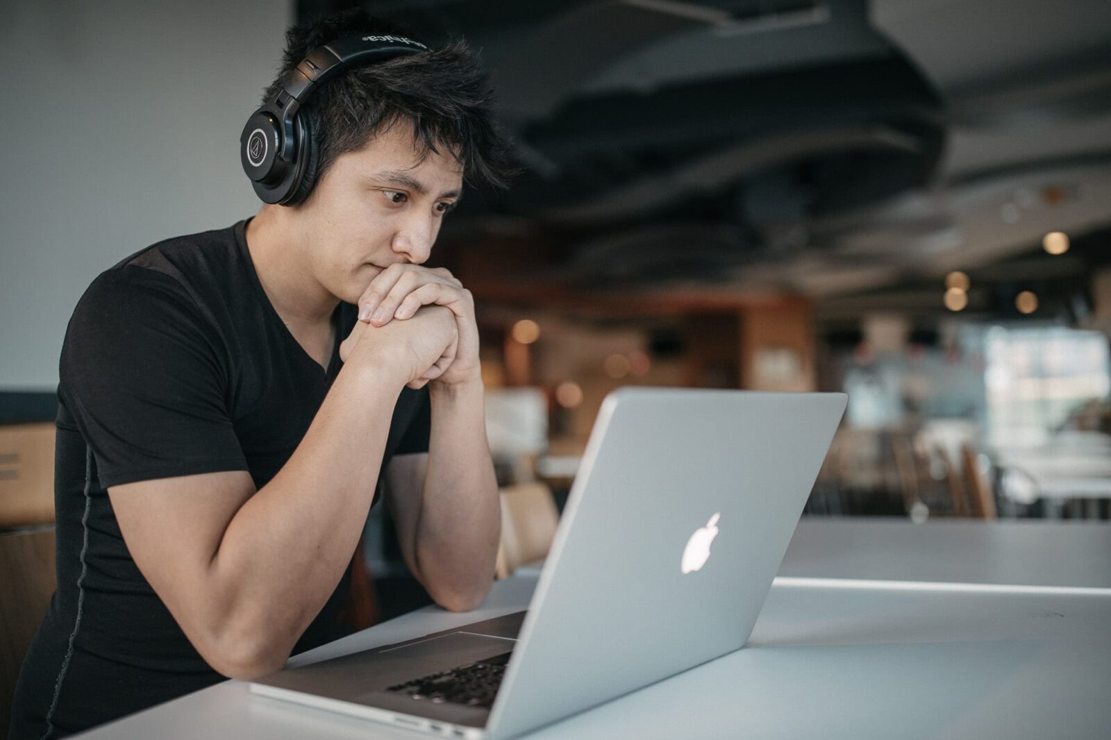 Depression at work - A young man wearing headphones looking at a laptop