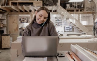 Flexible Working - A young woman using a phone in front of a laptop