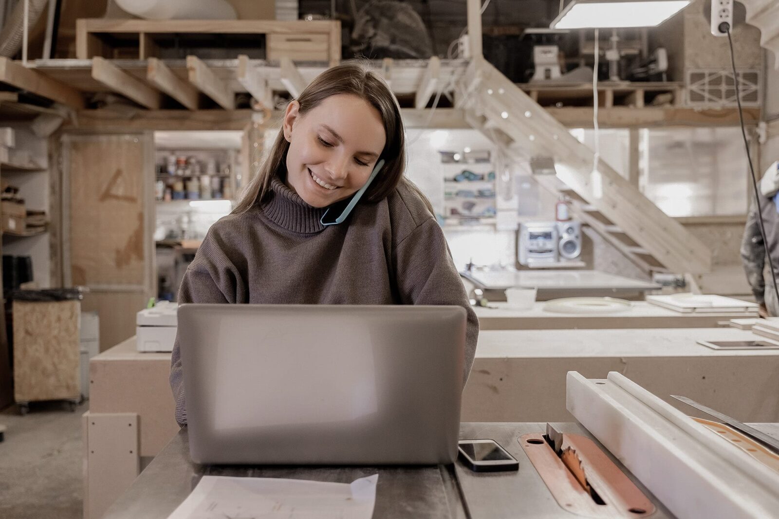 Flexible Working - A young woman using a phone in front of a laptop