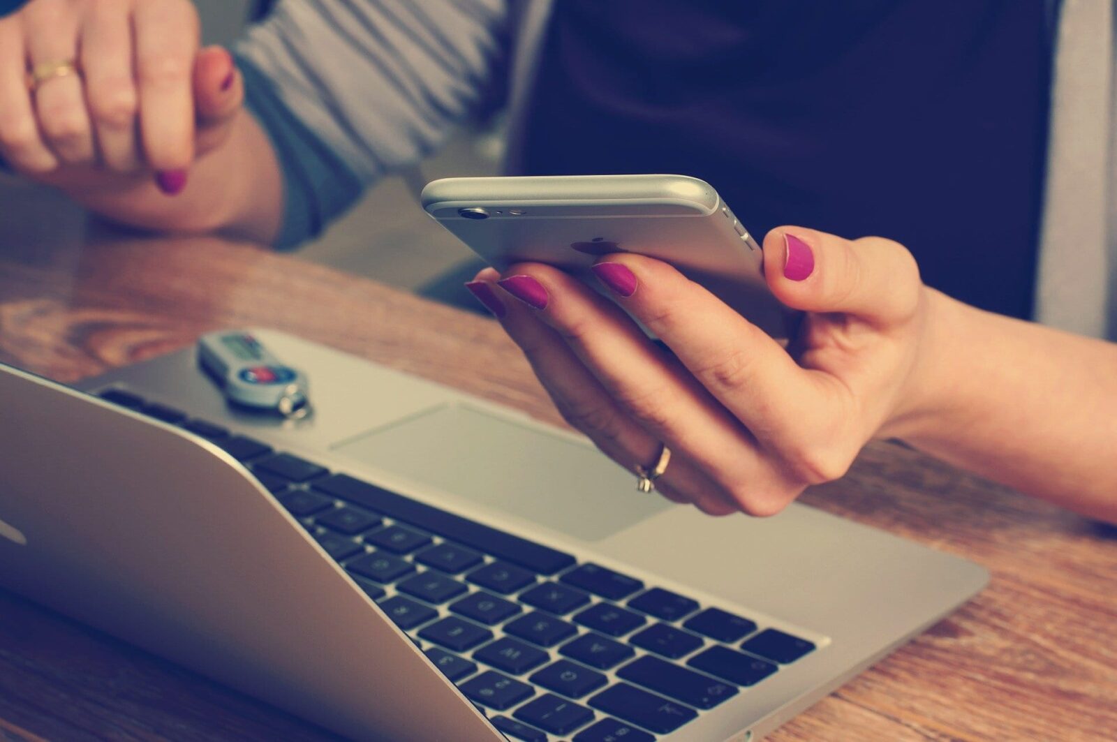 Content Creation Jobs - A woman holding an iPhone in front of a laptop