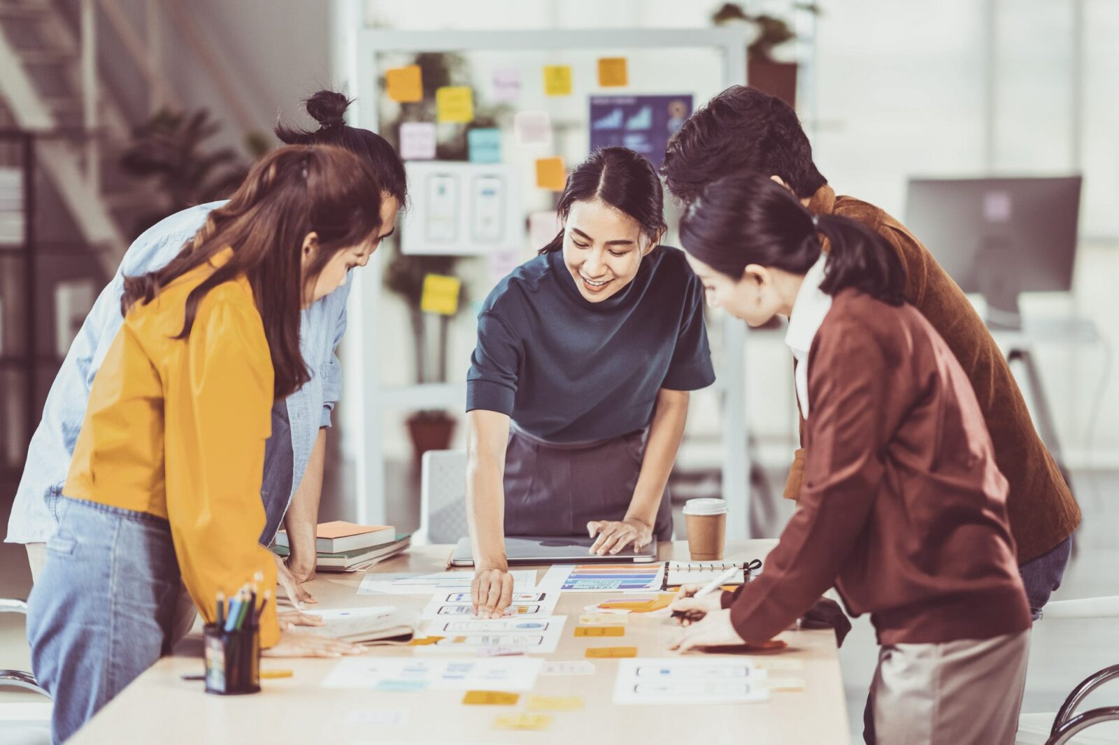 A group of diverse people standing around a table working on a project