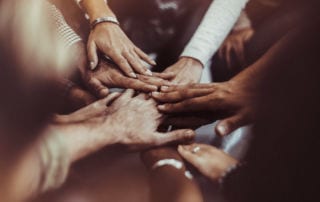 Remote Year. A diverse group of people holding their hands in the centre