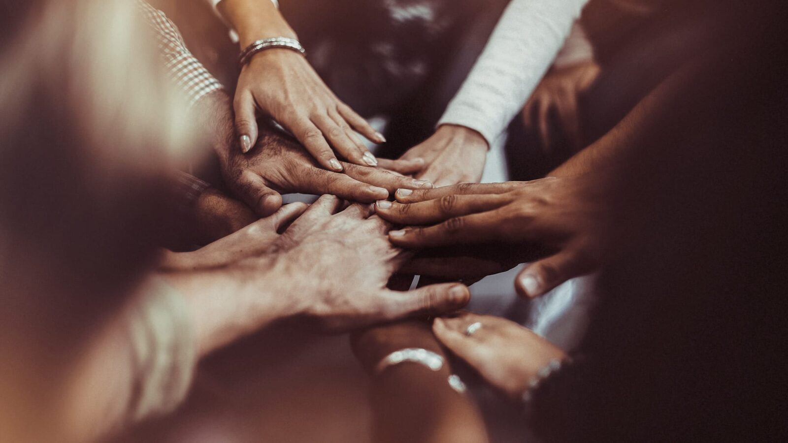 Remote Year. A diverse group of people holding their hands in the centre