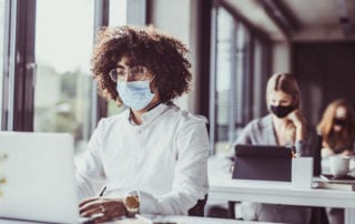 Man sitting at a desk working wearing a face mask