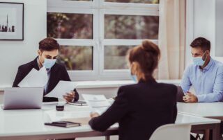 three people in a meeting wearing masks