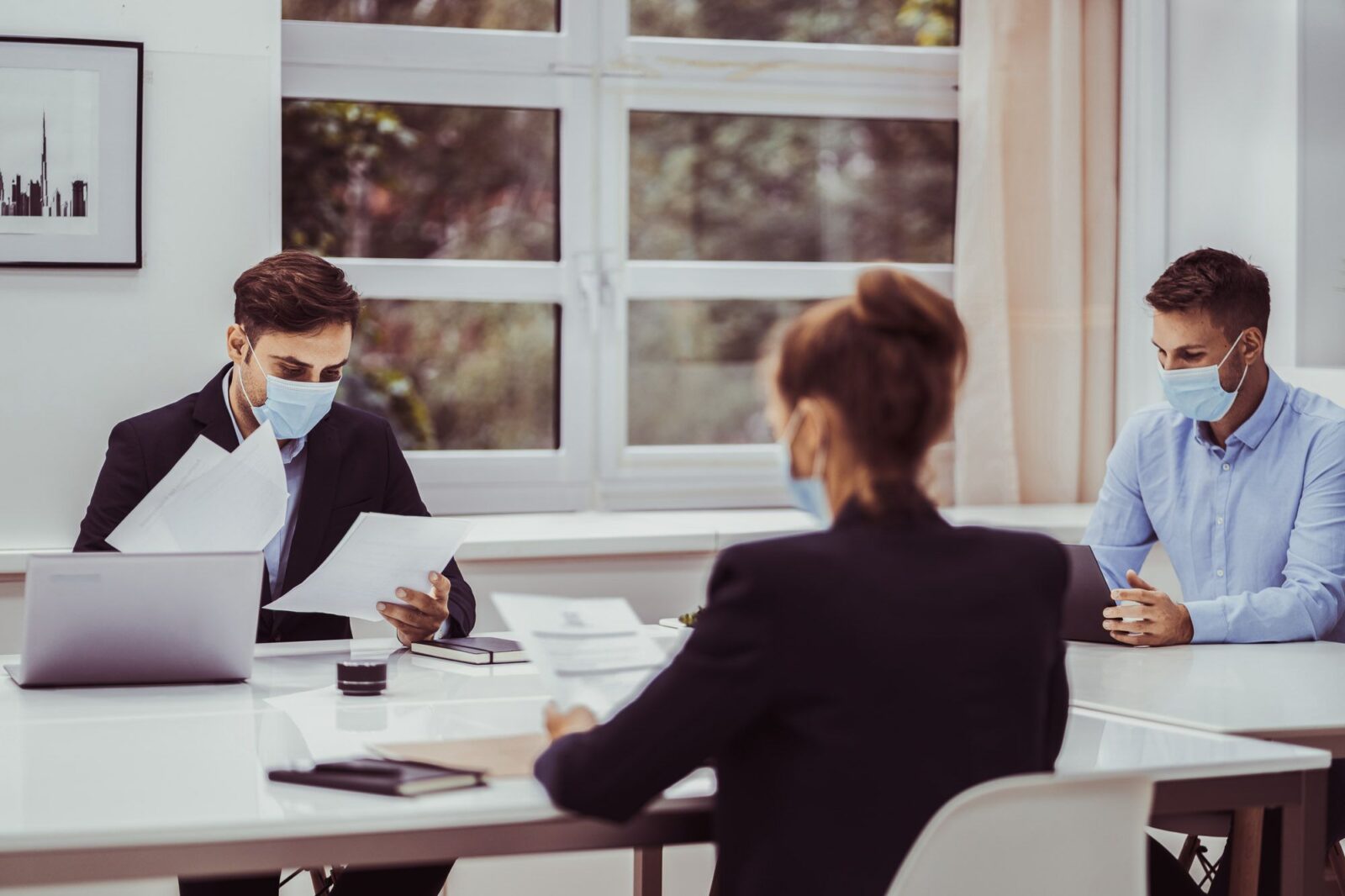 three people in a meeting wearing masks